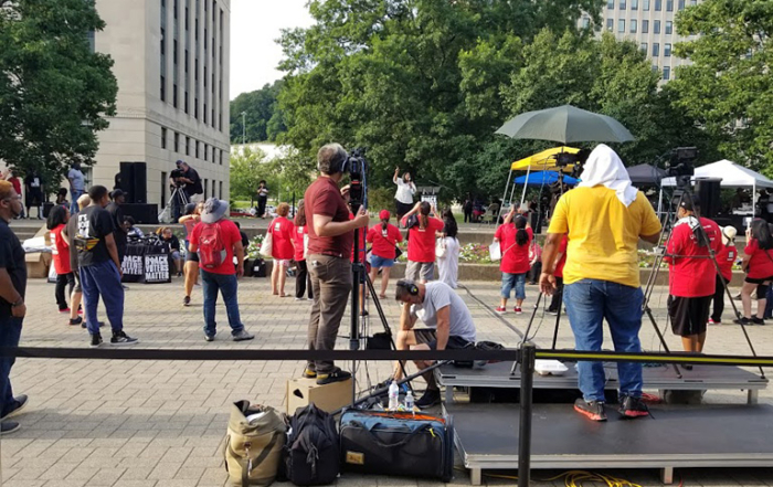 Dominic Desantos, center in red shirt, finds the right angle for Camera 1. Below him, audio tech Brian Garfield monitors the levels. In the background, left, camerman Tim Gordon can be seen getting reverse coverage.