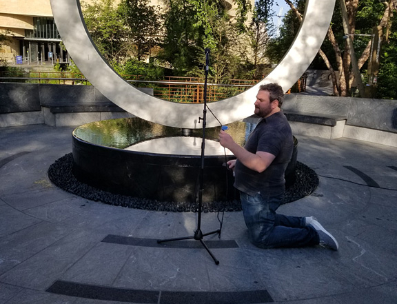 Streaming tech Dave Goldstein sets up the audio in front of the Warrior's Circle of Honor memorial.