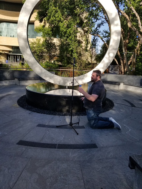Streaming tech Dave Goldstein sets up the audio in front of the Warrior's Circle of Honor memorial.