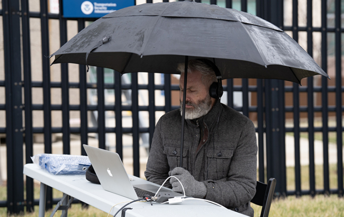 Director John Bogley huddles under an umbrella, but makes sure that everything is connected for the livestream.
