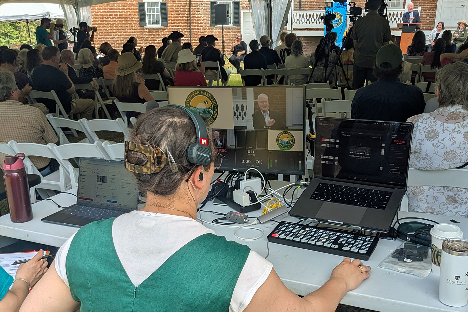 Southern Maryland 250: Liberty and Legacy Analee Wong oversees the streaming setup, as Sen. Chris Van Hollen (onscreen and in background) speaks to the audience.